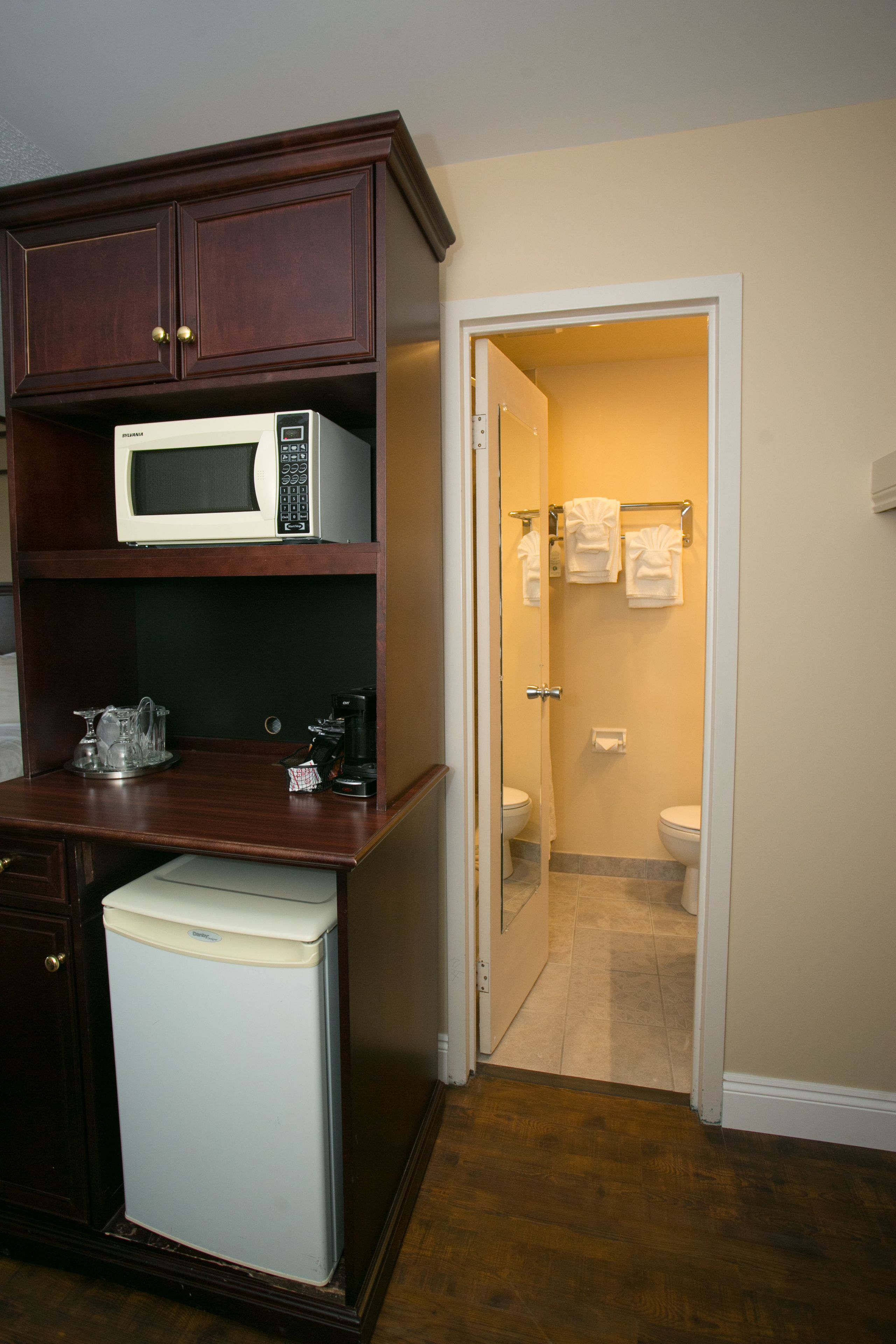 A compact kitchenette with a microwave, coffee maker, and refrigerator.