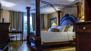 Una cama con dosel y tablero de madera, un escritorio con una silla y una ventana con cortinas.