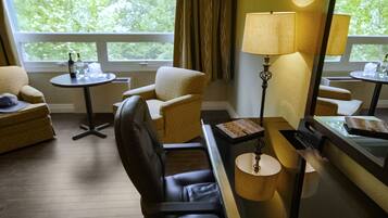 Habitación de hotel con sofá, sillón, una mesita redonda y una lámpara.