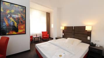 Habitación de hotel con cama, escritorio, silla y un cuadro en la pared.