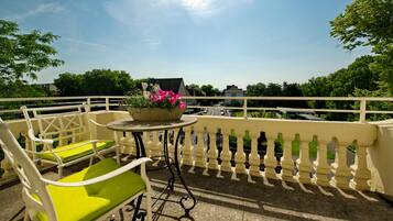 A balcony with a table, chairs, and a potted plant.