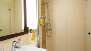 A bathroom with a sink, mirror, shower, and toilet.