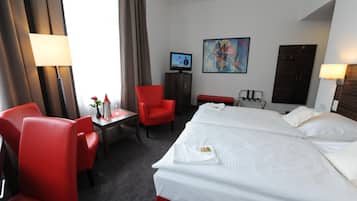 A hotel room with a bed, a desk, a chair, a television, and a painting on the wall.