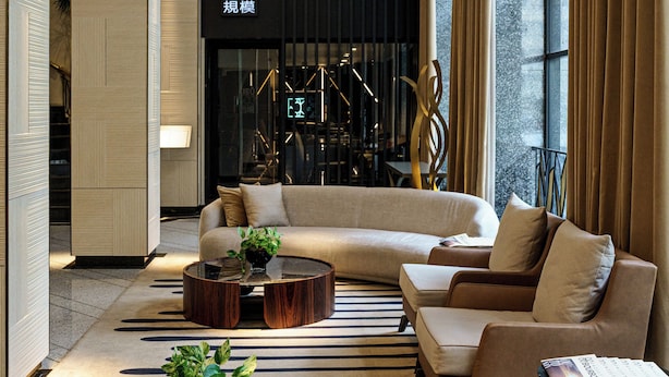 A modern hotel lobby with a sofa, coffee table, and potted plants.
