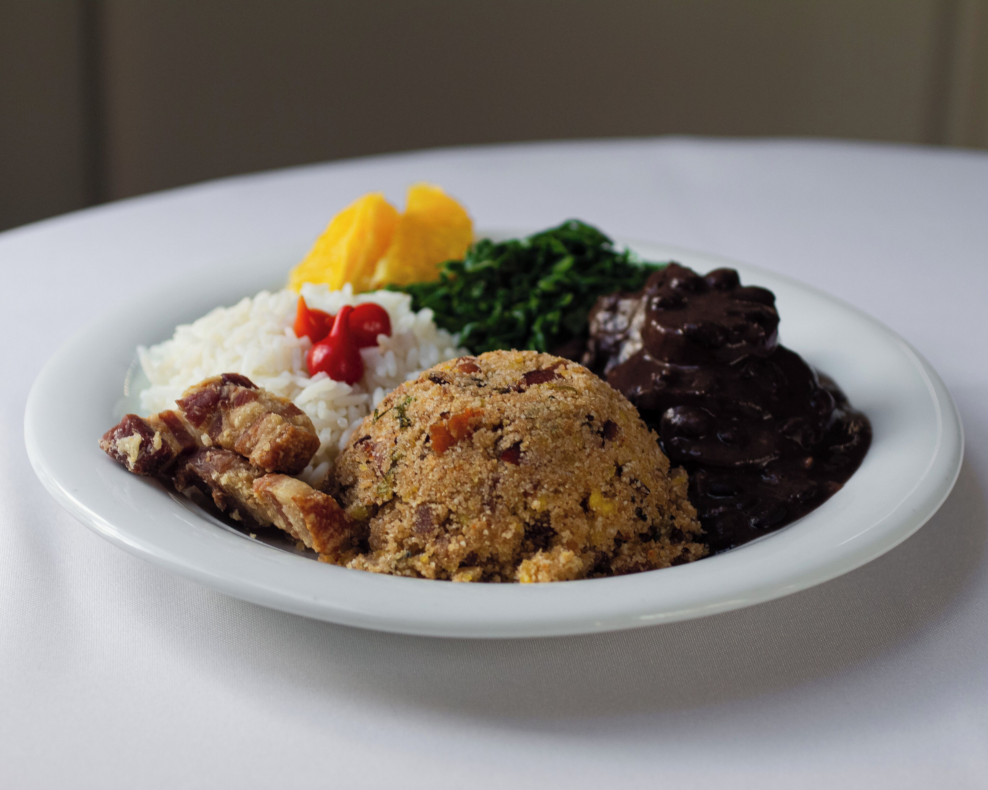 Prato de comida com arroz, carne, um item empanado e um molho escuro.