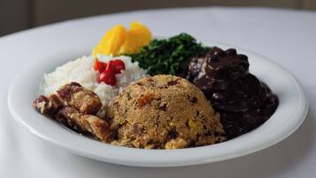 Prato de comida com arroz, carne, um item empanado e um molho escuro.