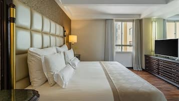 A hotel room with a large bed, a television, a dresser, and a window with curtains.