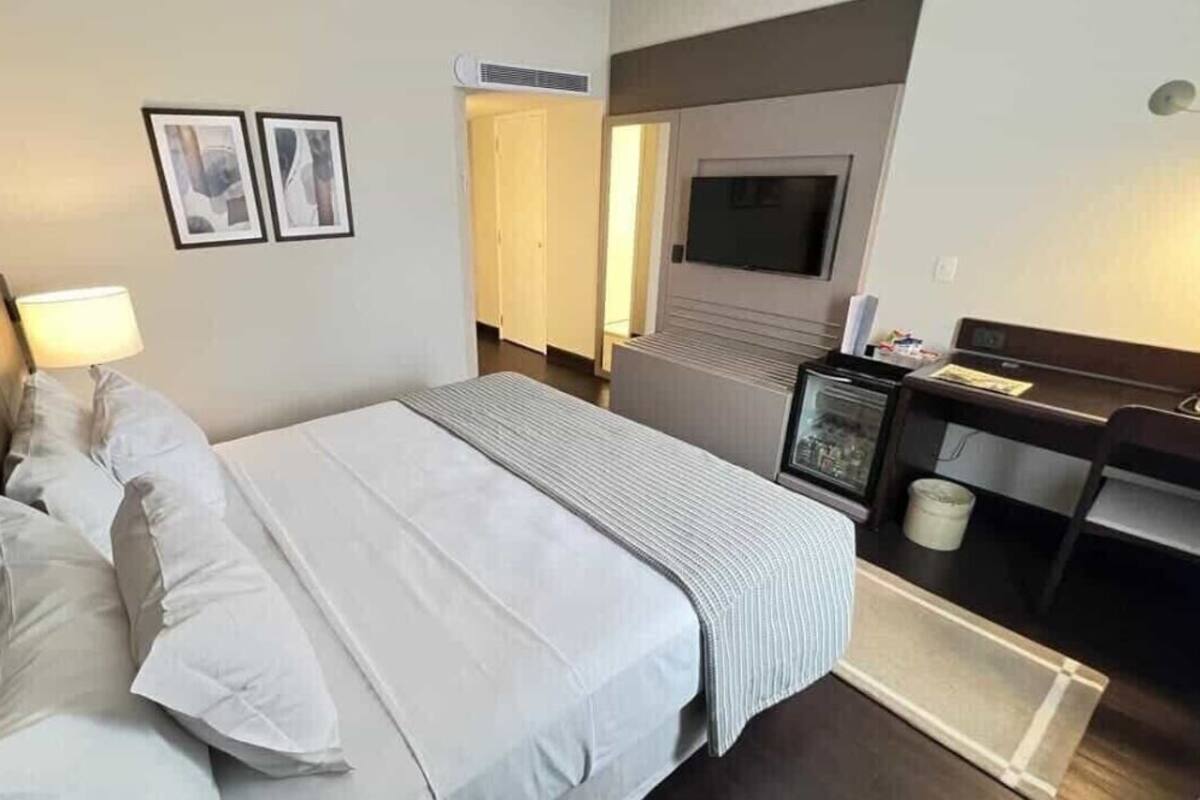 Una habitación de hotel con cama, escritorio, televisor y una pequeña kitchenette.
