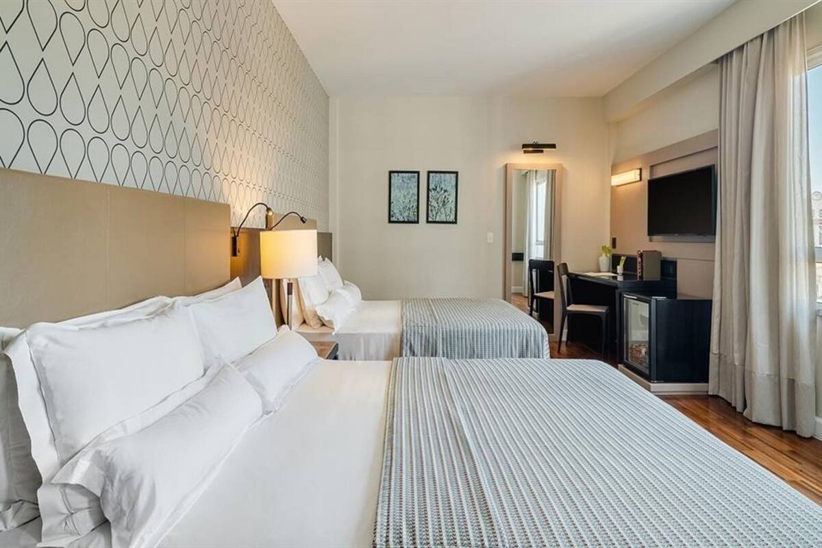 Habitación de hotel con dos camas, un escritorio, un televisor y un minibar.
