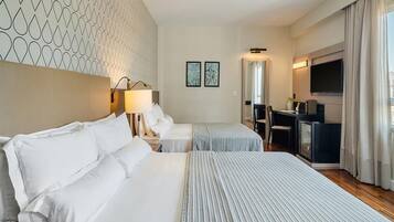 A hotel room with two beds, a desk, a TV, and a minibar.