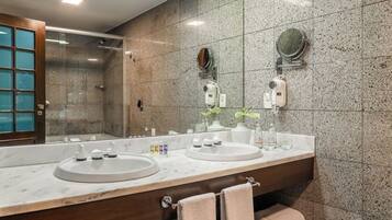 Un baño moderno con dos lavamanos, ducha y un espejo grande.
