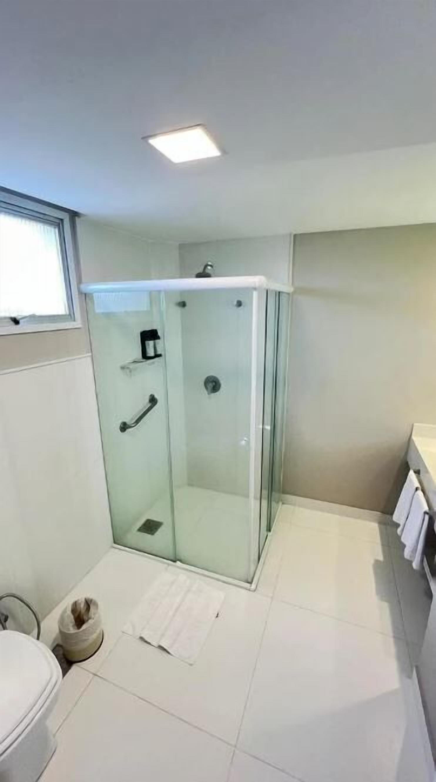 Un baño con cabina de ducha de vidrio, inodoro y perchero para toallas.