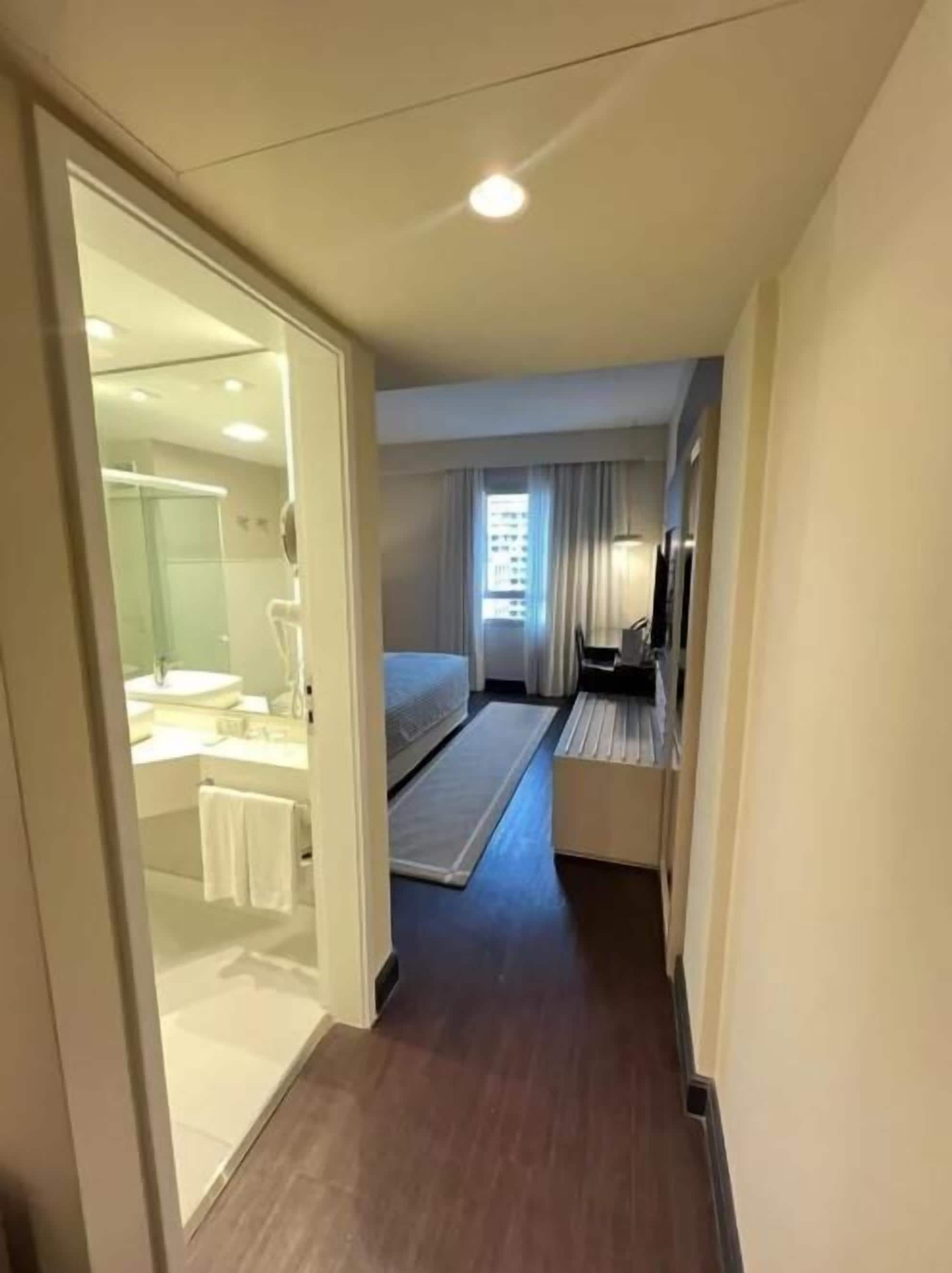 Une chambre d’hôtel avec une salle de bain, un lit, une télévision et une fenêtre avec des rideaux.