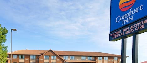 A Comfort Inn hotel with a clear sky, a well-maintained lawn, and a welcoming sign.