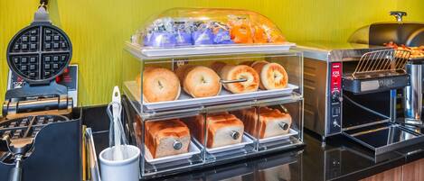 A breakfast buffet with various food items and a waffle maker.