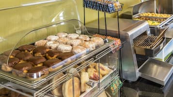 A buffet with various baked goods including pastries, muffins, and bread.