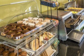 A buffet with various baked goods including pastries, muffins, and bread.