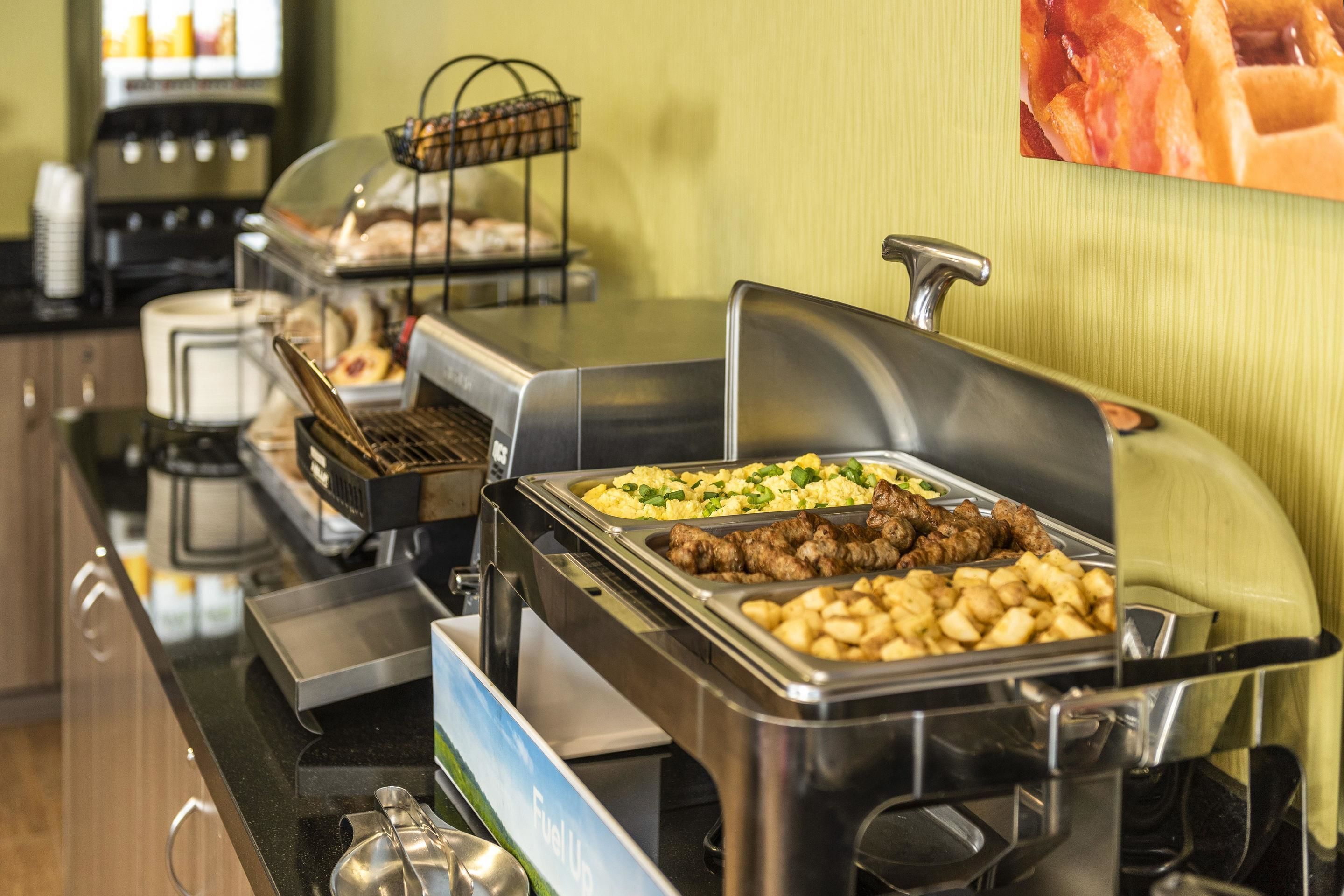 A buffet setup with various food items, including meats, potatoes, and a salad.