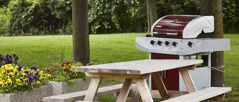 Una mesa de picnic con una parrilla de barbacoa en un parque.