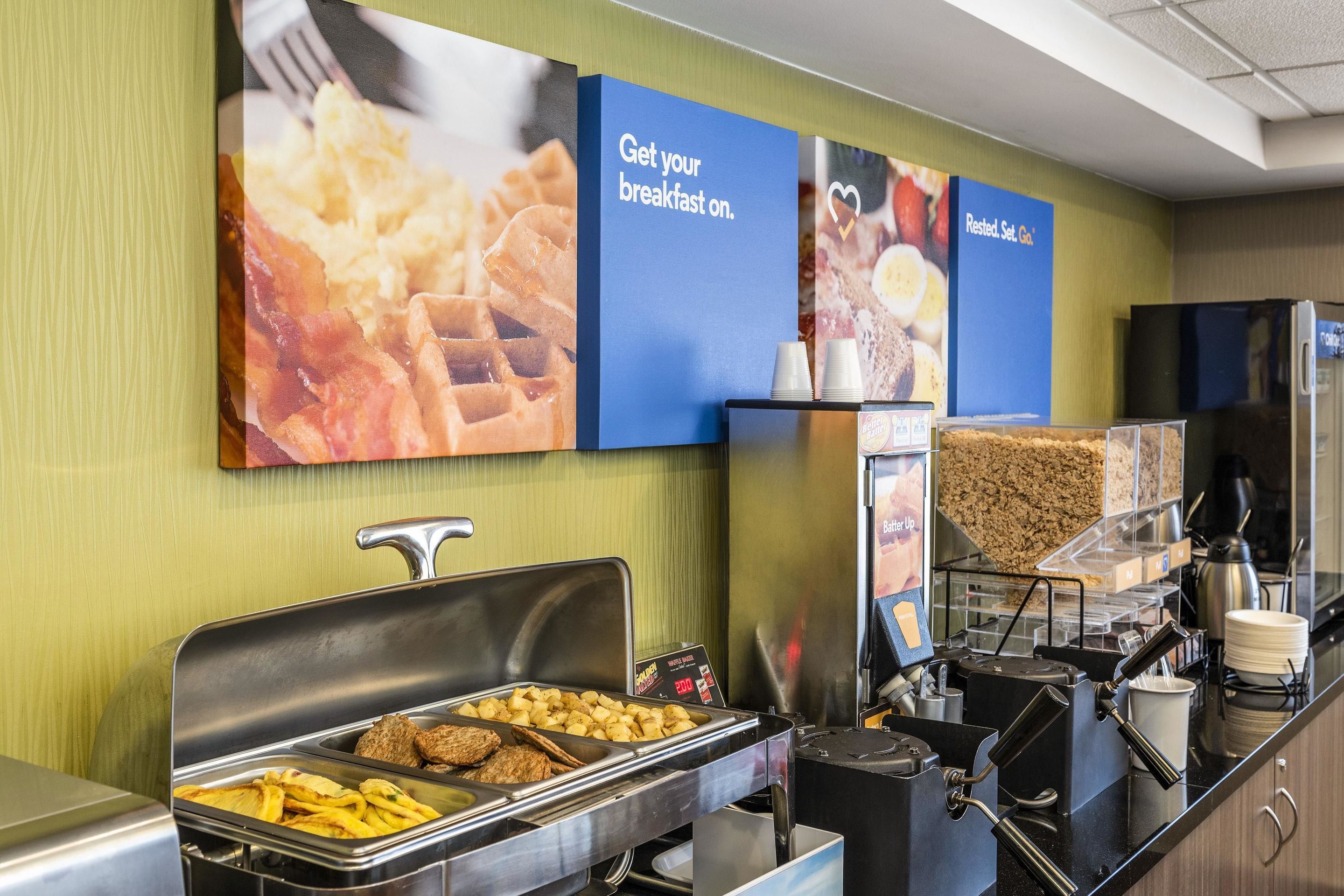 A buffet area with various food options, including waffles, bacon, and French fries.