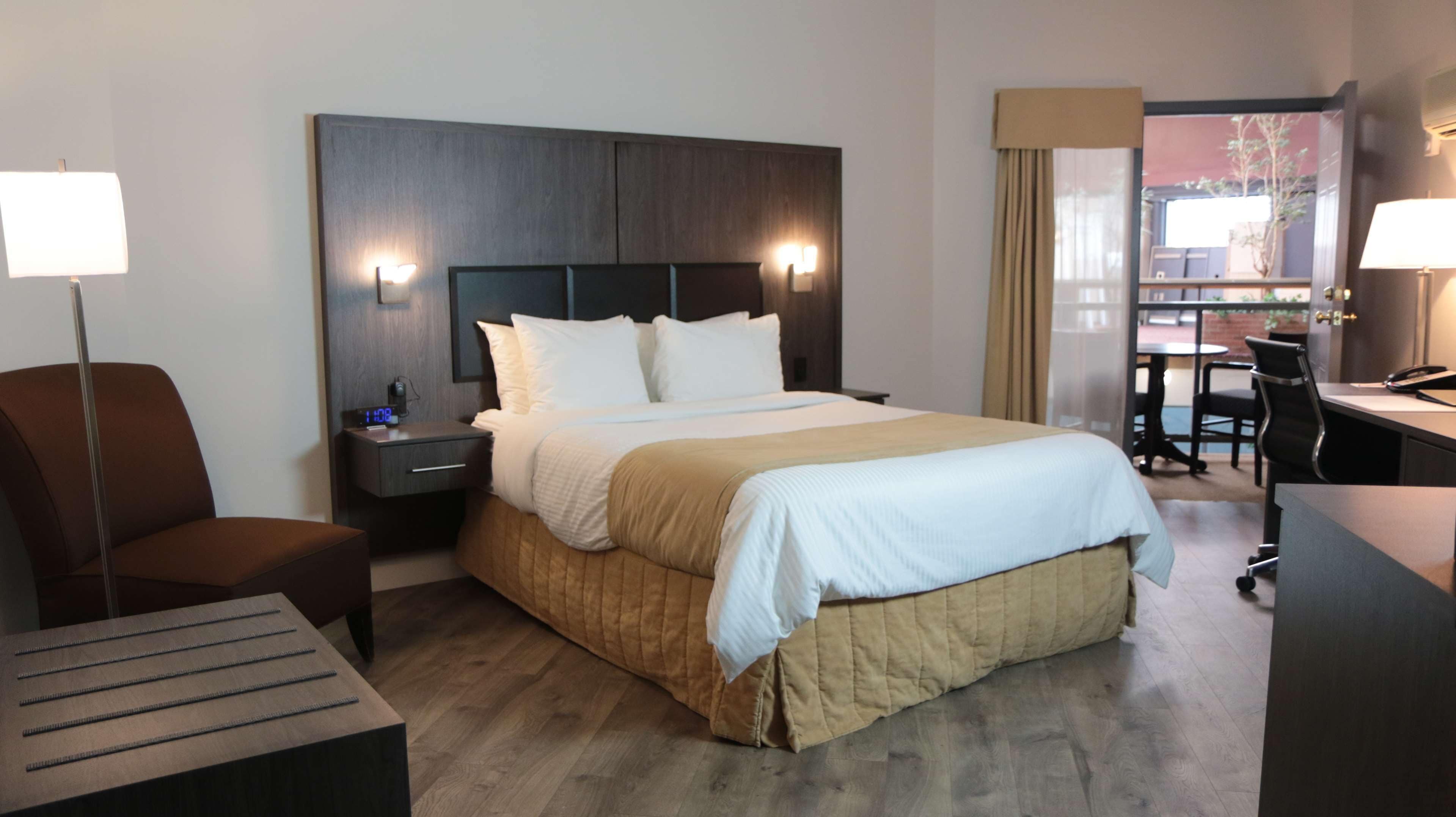 Una habitación de hotel con cama, mesitas de noche, escritorio, silla y lámpara.