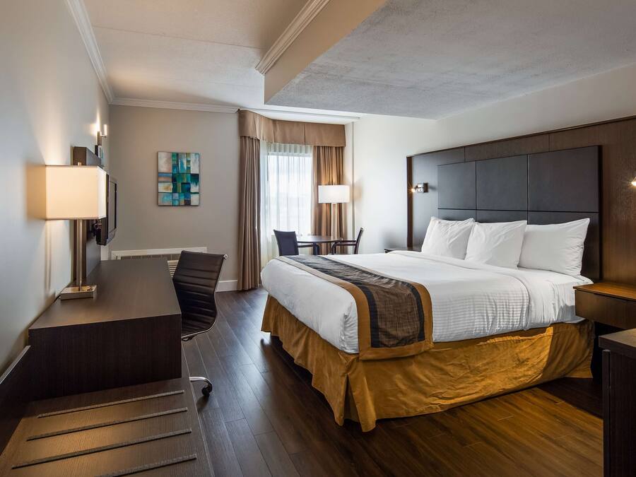 A hotel room with a large bed, a desk, a chair, and a television.