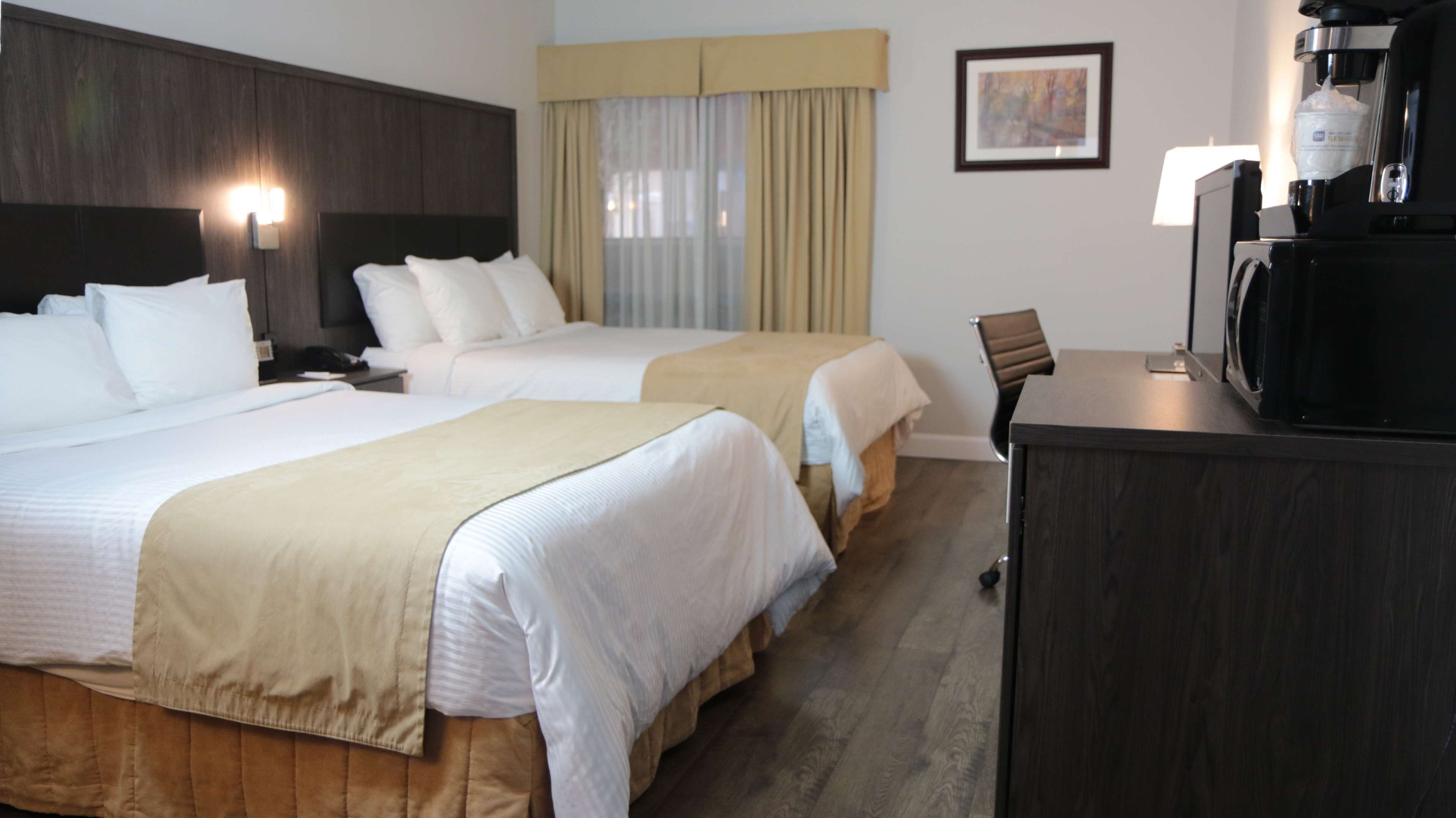 A hotel room with two beds, a coffee machine, and a chair.