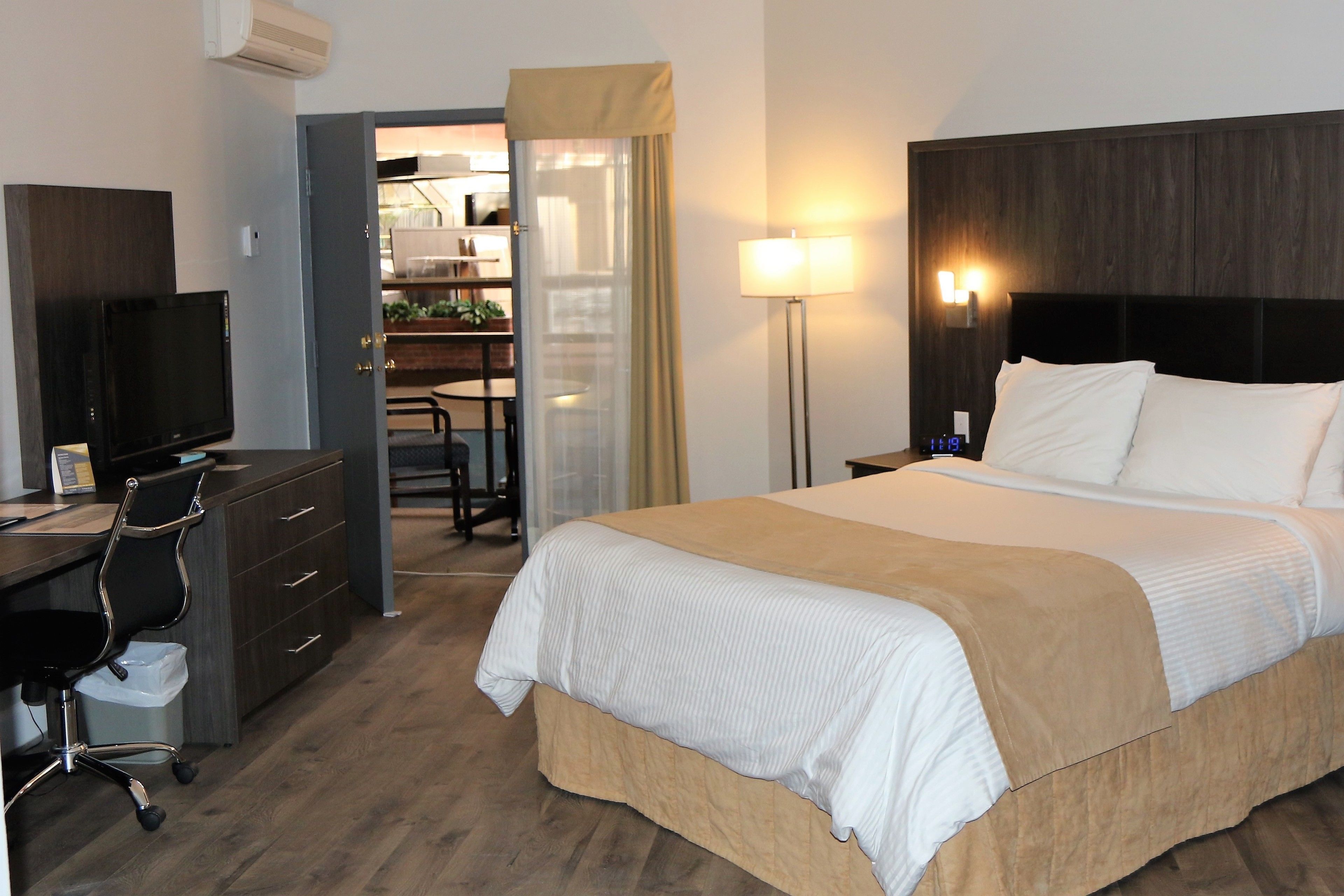 Una habitación de hotel con cama, escritorio, silla y televisión.