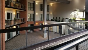 A modern building with a glass railing, multiple floors, and a courtyard with potted plants. - Best Western Laval-Montreal (Laval)
