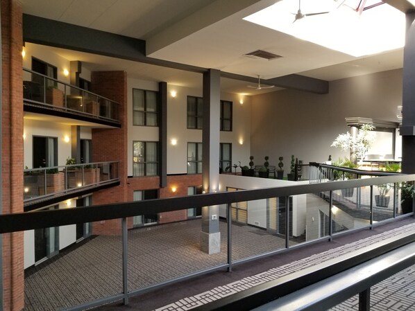 A modern building with a glass railing, multiple floors, and a courtyard with potted plants. - Best Western Laval-Montreal (Laval)