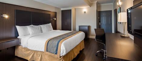 Habitación de hotel con cama, escritorio, silla, televisor y armario.