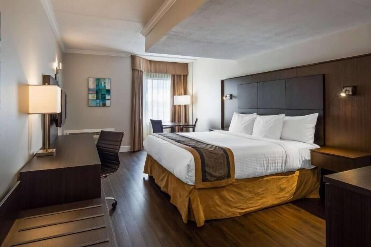 A hotel room with a bed, desk, chair, and a view of the outdoors.