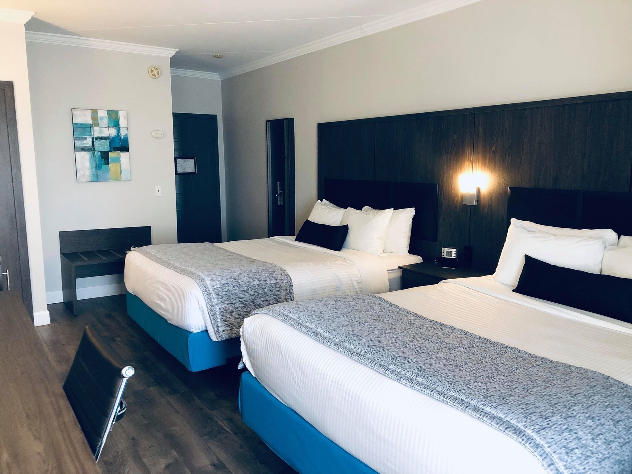 Une chambre d’hôtel avec deux lits, une table de chevet avec une lampe et une œuvre d’art accrochée au mur.