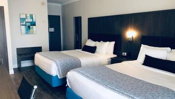 Habitación de hotel con dos camas, una mesita de noche con lámpara y una obra de arte colgada en la pared.