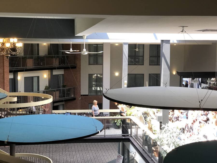 A multi-level indoor space with a central open area, multiple balconies, and hanging light fixtures.