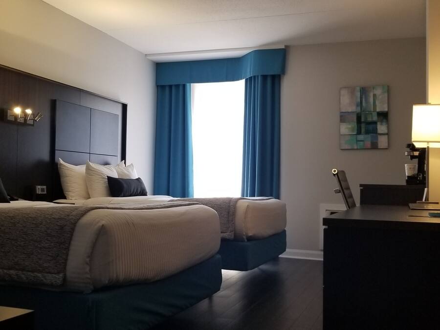 Habitación de hotel con dos camas, un escritorio, una lámpara y un televisor.