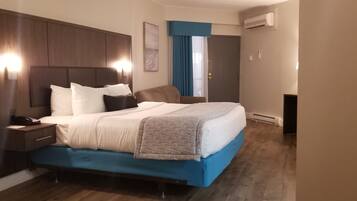Een hotelkamer met een groot bed, nachtkastje, bureau en een airconditioning.