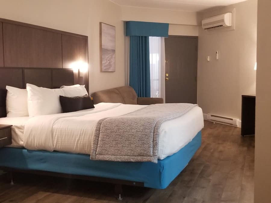 Een hotelkamer met een groot bed, nachtkastje, bureau en een airconditioning.