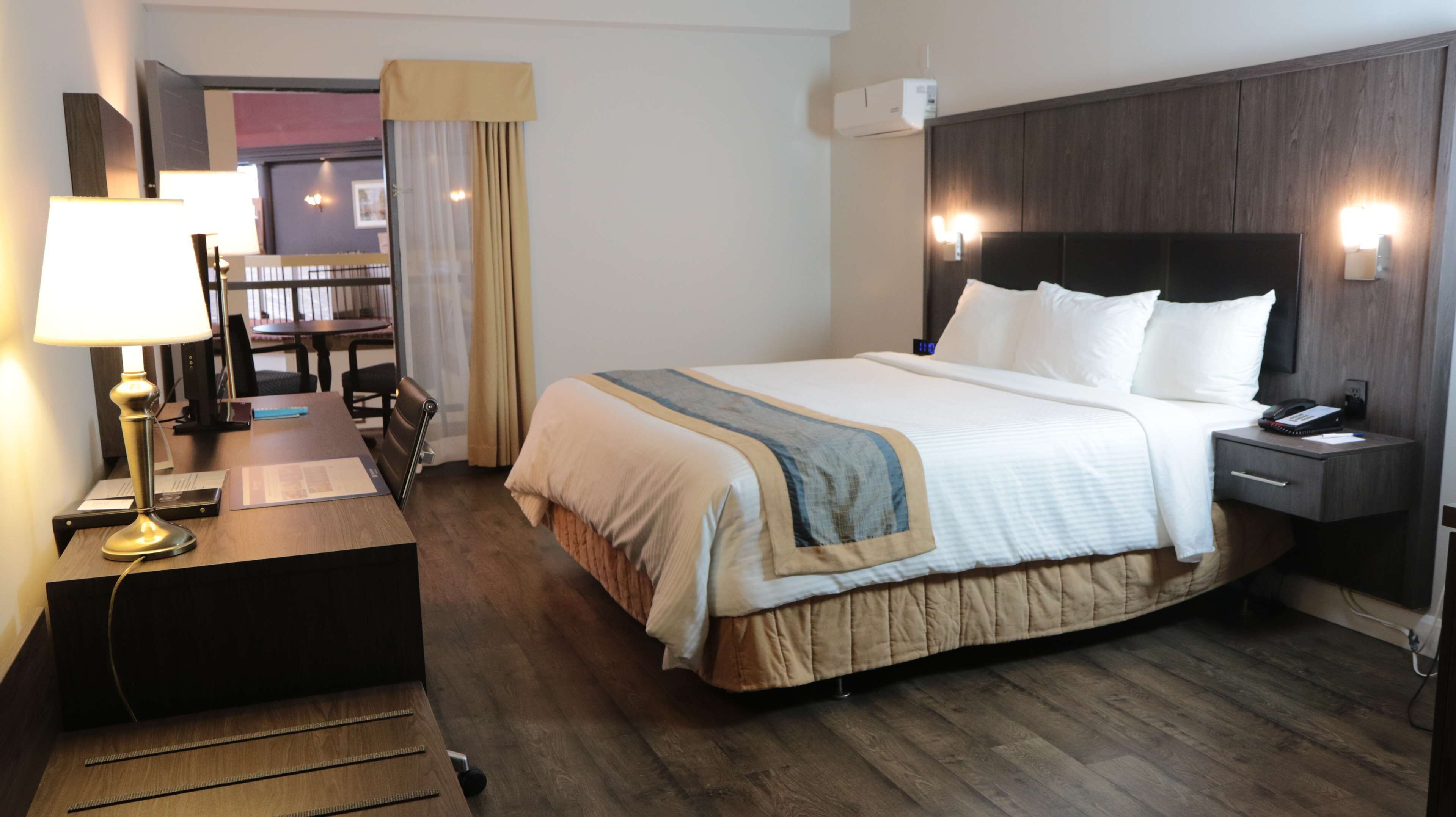Une chambre d’hôtel comprenant un lit, une table de chevet, une lampe et un bureau avec une chaise.