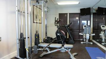 A gym with exercise equipment, a mirror, and a blue mat.