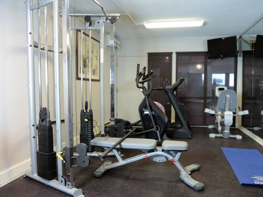 A gym with exercise equipment, a mirror, and a blue mat.