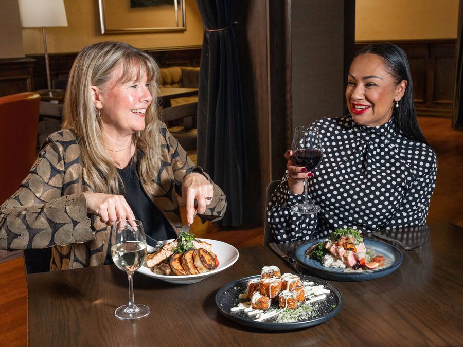 Two people dining at a table with plates of food and wine glasses.