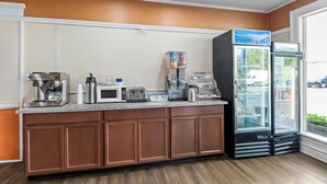 A kitchenette with a coffee machine, toaster, kettle, and a refrigerator stocked with beverages.
