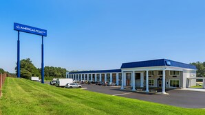 A motel with a row of single-story buildings, a parking lot, and a large blue sign.