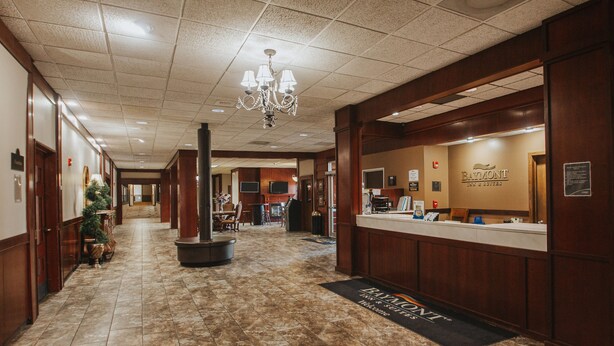 Un vestíbulo de hotel con un mostrador de recepción, un candelabro, un árbol de Navidad y un cartel de Baymont Inn & Suites.