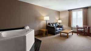 Una habitación de hotel con bañera, sofá, mesa de centro y mesa de comedor.