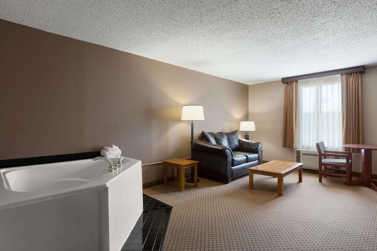 Una habitación de hotel con bañera, sofá, mesa de centro y mesa de comedor.