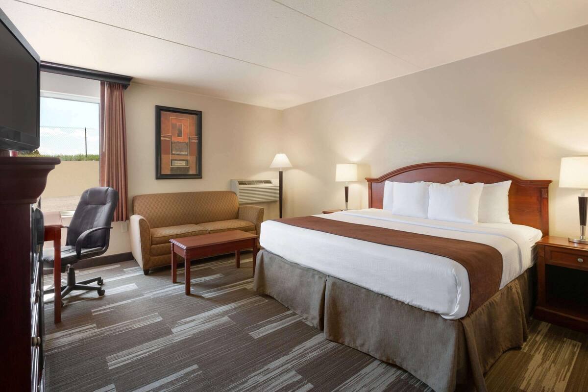 Una habitación de hotel con cama, escritorio, silla y televisión.