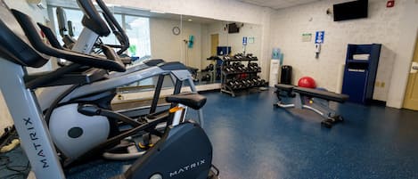 A gym with treadmills, dumbbells, and exercise balls.
