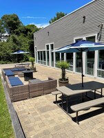 An outdoor patio area with wicker furniture, a table, and a bench.